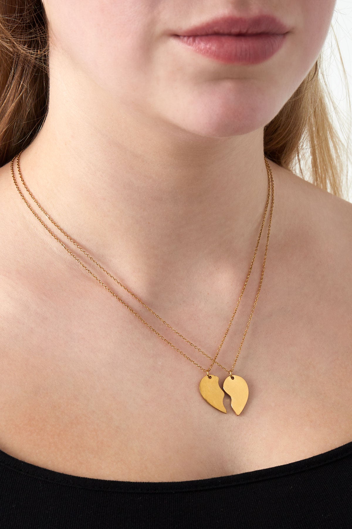 Close-up of a woman wearing a gold two-piece best friend necklace set with broken heart pendants