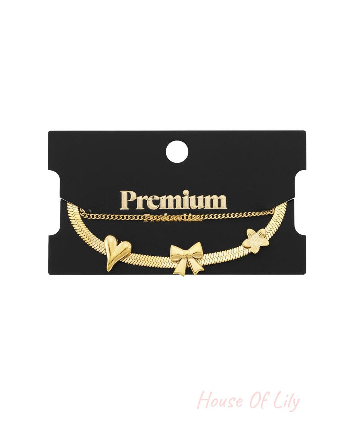 Gold-tone bangle set featuring a flat herringbone chain with heart, bow, and flower charms and a delicate link chain.