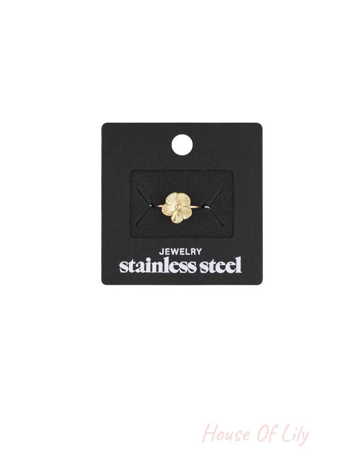 Gold flower ring displayed on a black card holder labeled stainless steel jewelry