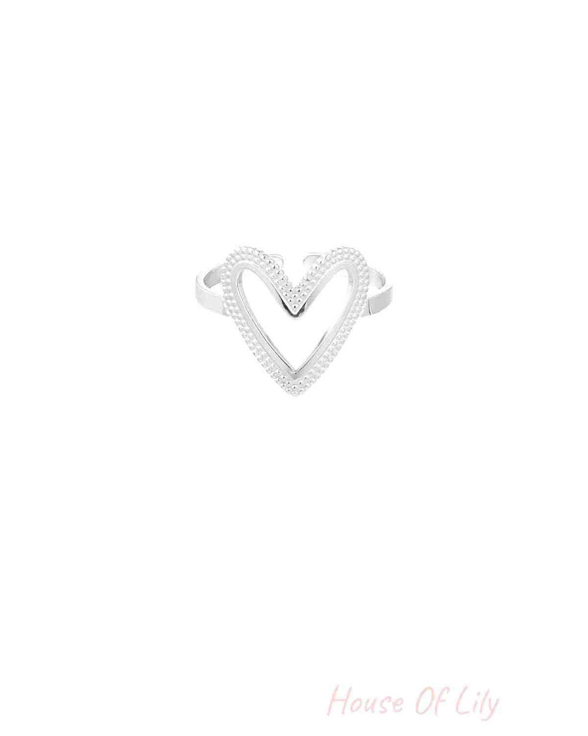 Silver-toned heart-shaped ring with textured beading shown against white background