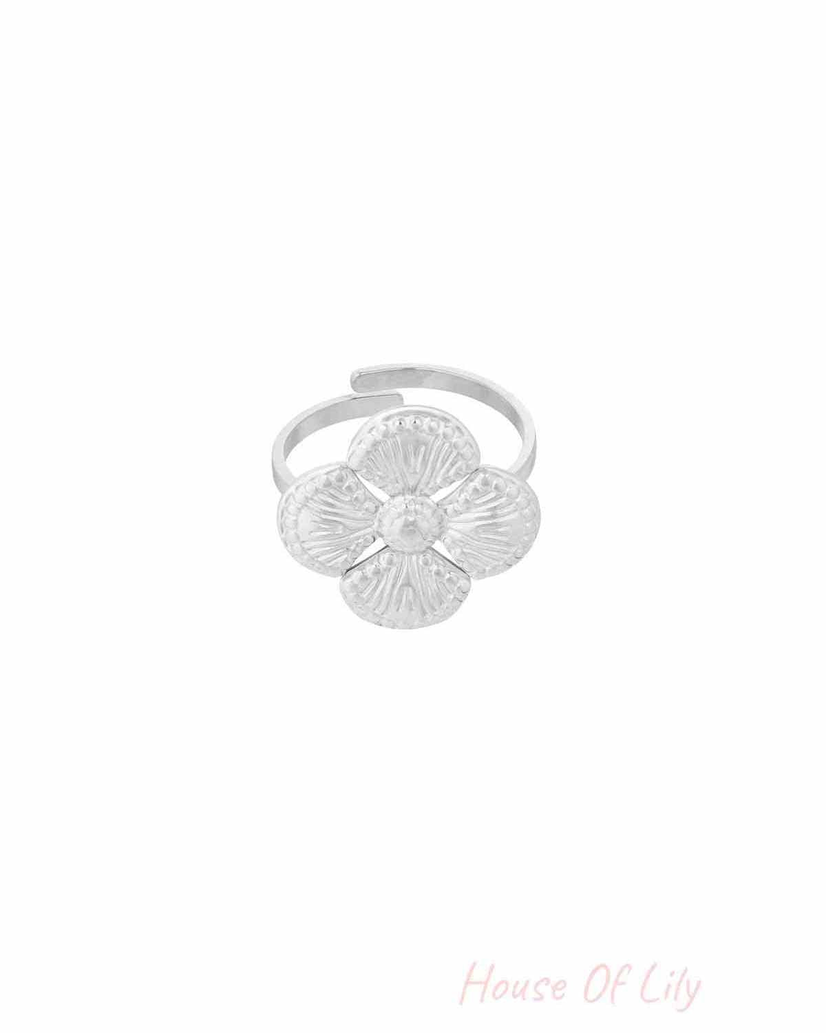 Close-up of a silver textured clover statement ring with four petals on a white background