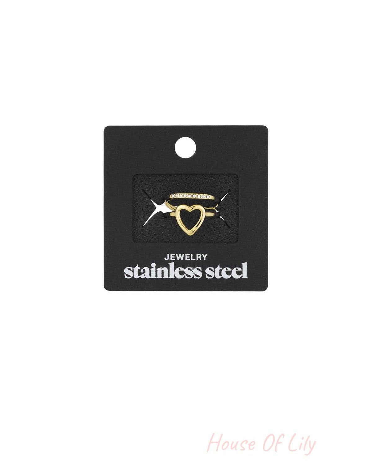 Gold heart and rhinestone accent rings displayed on a black card labeled 'stainless steel jewelry'