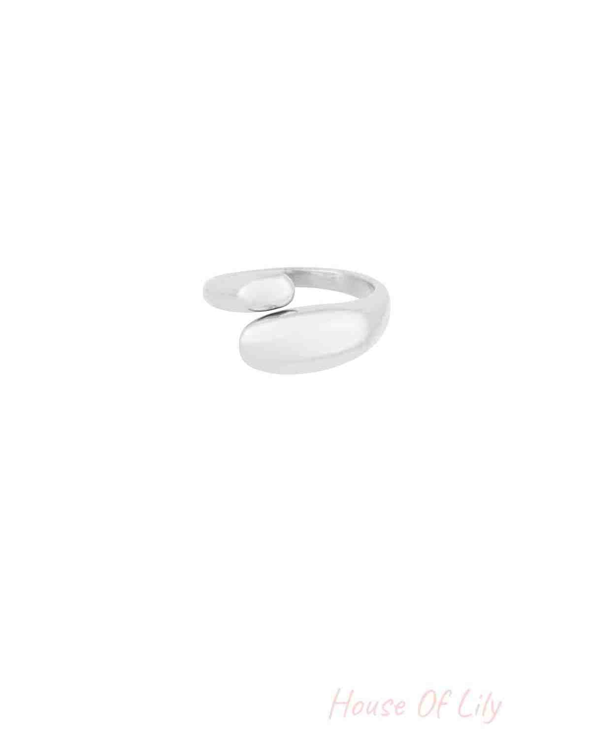 Close-up of silver-toned version of the sculptural open ring with smooth rounded ends on white background