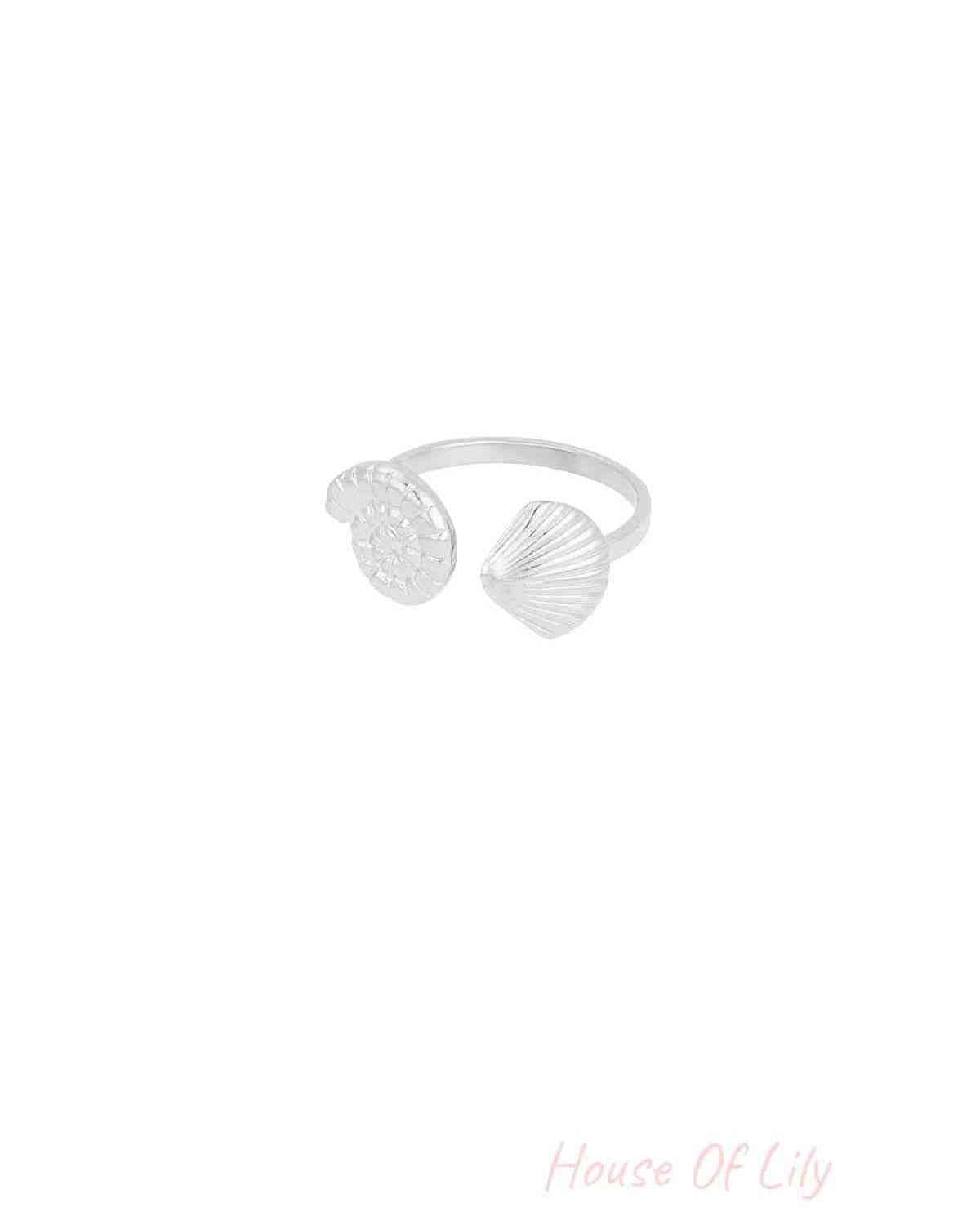 Silver open ring with detailed seashell and spiral shell motifs on white background