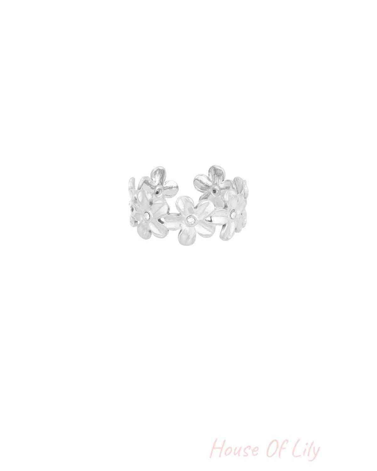 Silver daisy flower statement ring with crystal centres on white background, angled view