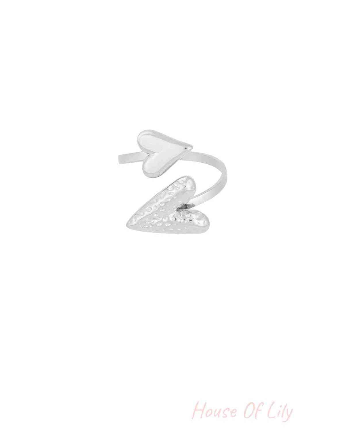 Silver adjustable wrap ring with two hearts, featuring one smooth and one hammered heart shape, isolated on white background