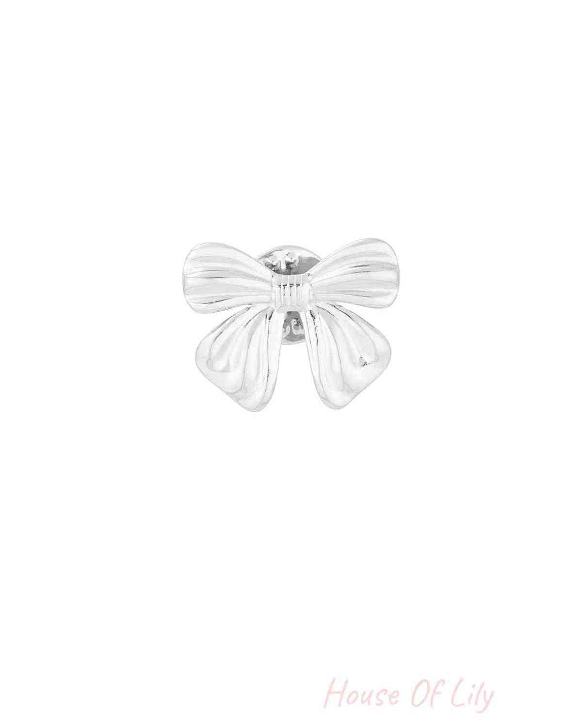 Close-up of polished silver bow-shaped brooch with smooth curves on white background