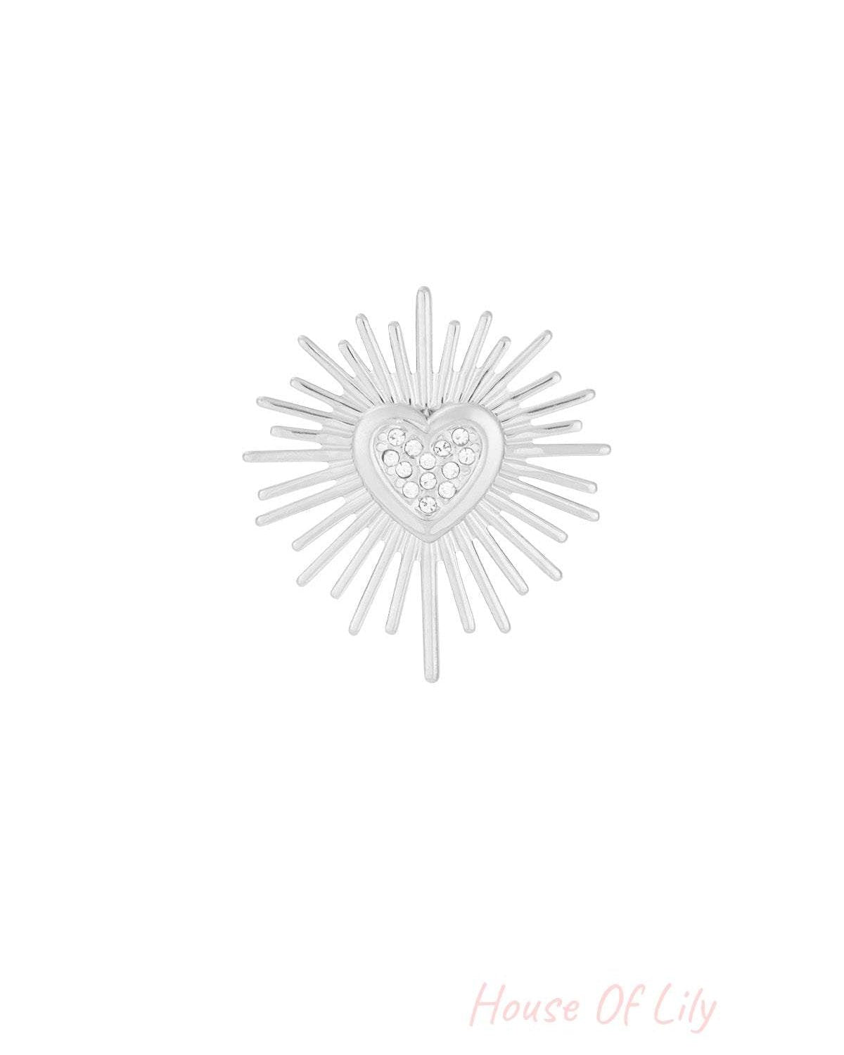 Silver tone brooch with radiant sunburst pattern and stone-studded heart centerpiece isolated on white background