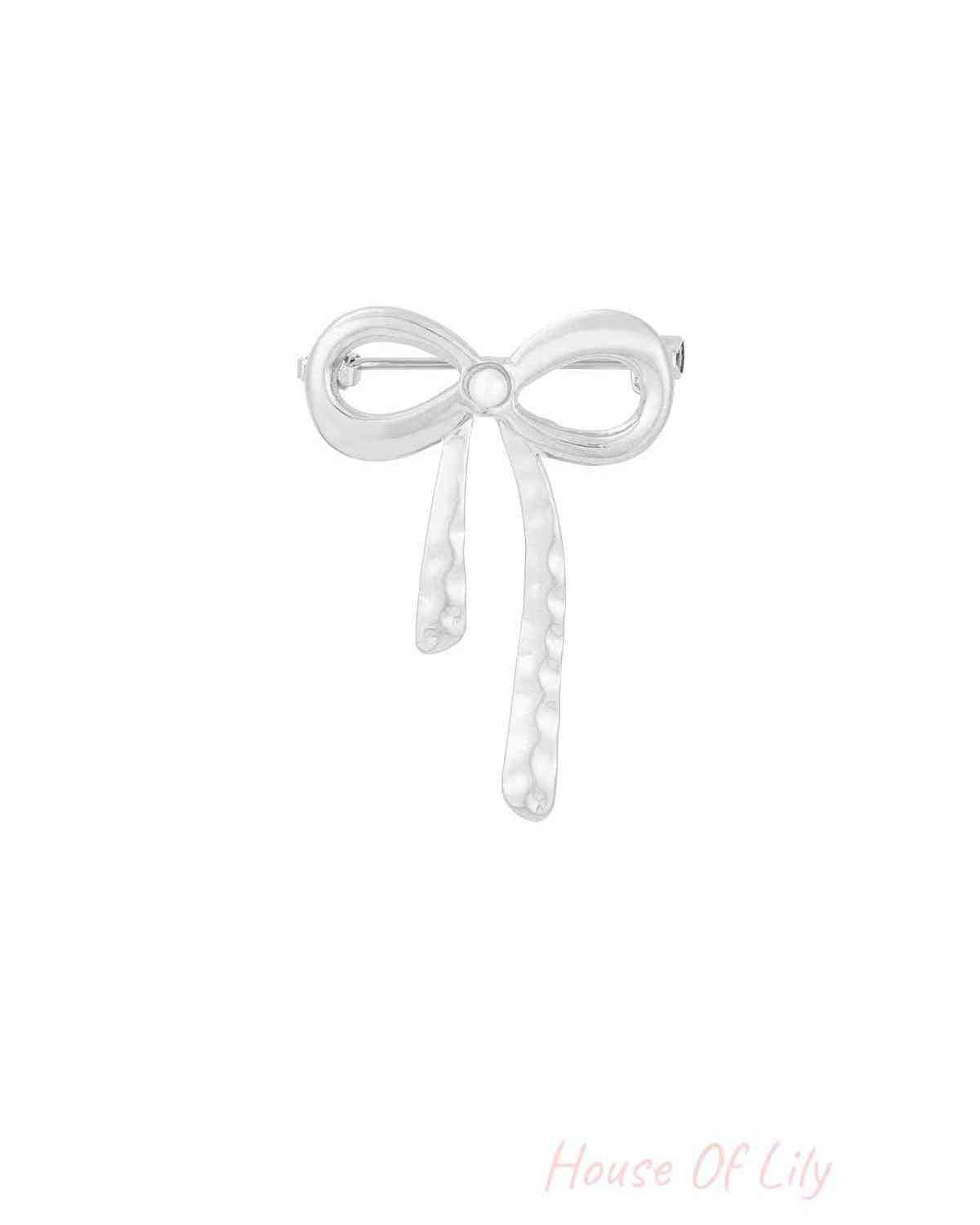Silver hammered bow brooch with pearl center on white background