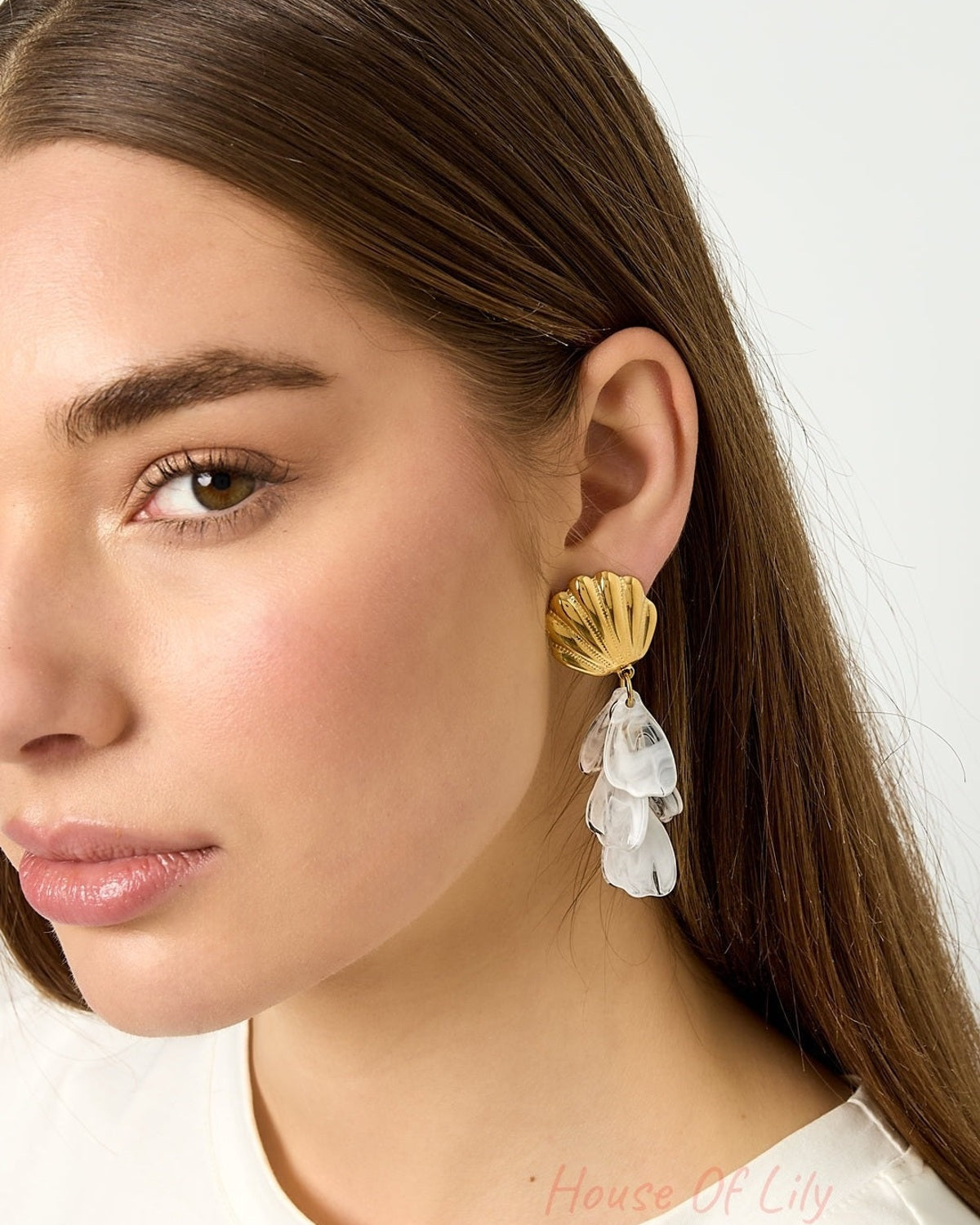 Gold shell drop earrings with dangling marbled white translucent petals on white background