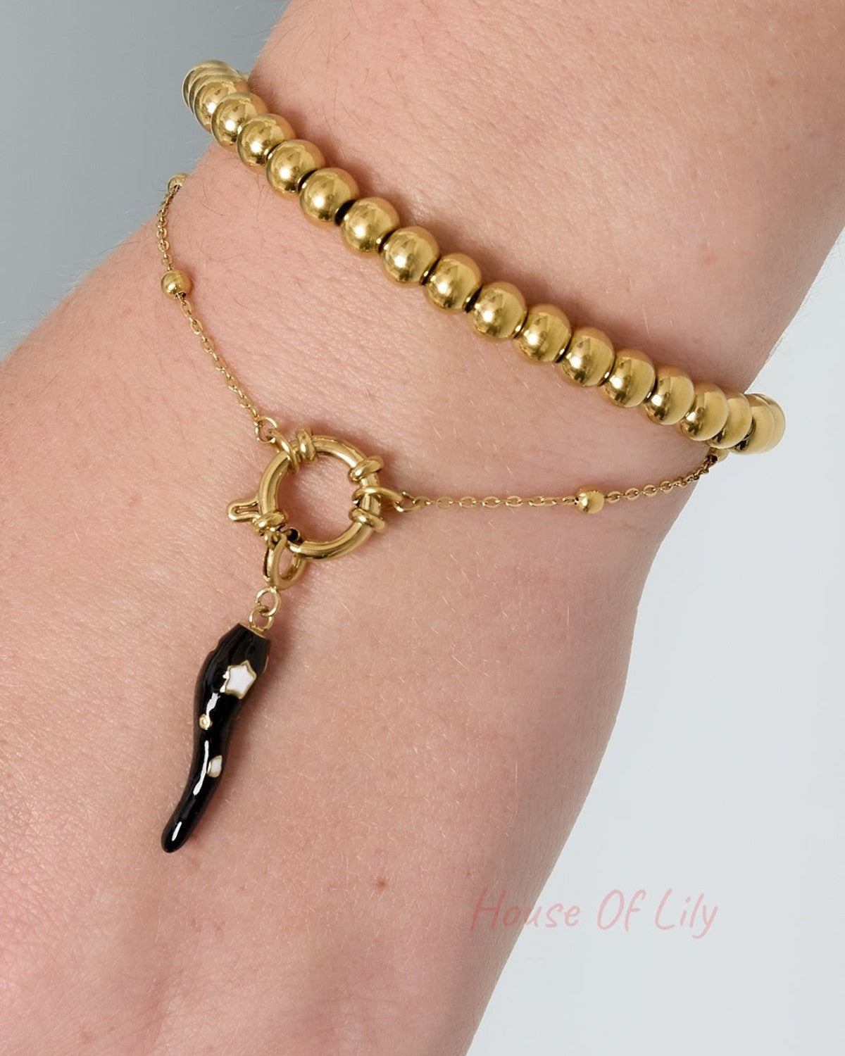 Close-up of gold-toned minimalist beaded bracelet worn alongside a gold beaded bracelet on wrist