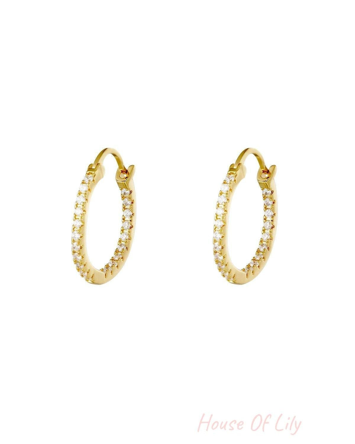 Pair of gold hoop earrings studded with clear stones on white background