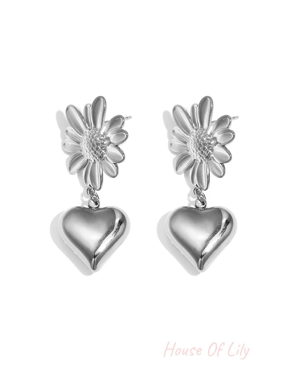 Pair of silver drop earrings with flower tops and hanging heart charms on white background