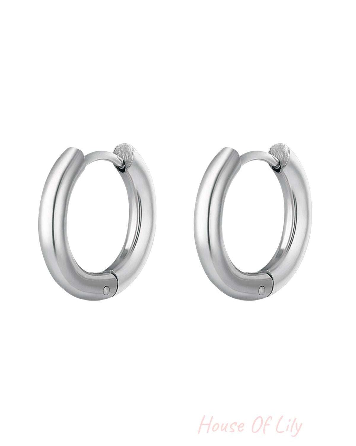 Pair of polished silver-colored stainless steel hoop earrings with rounded smooth design on white background