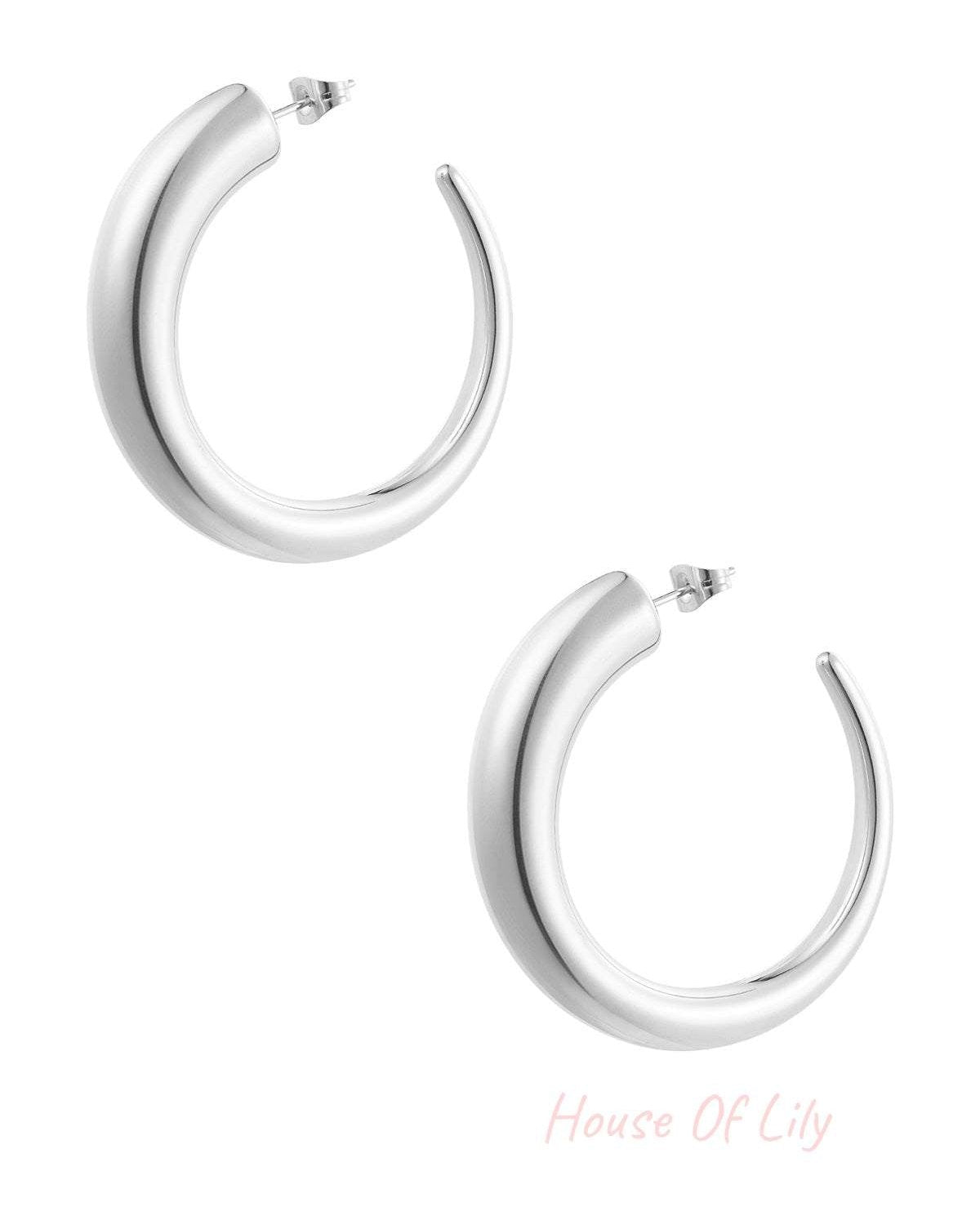 Pair of chunky silver curved hoop earrings on white background