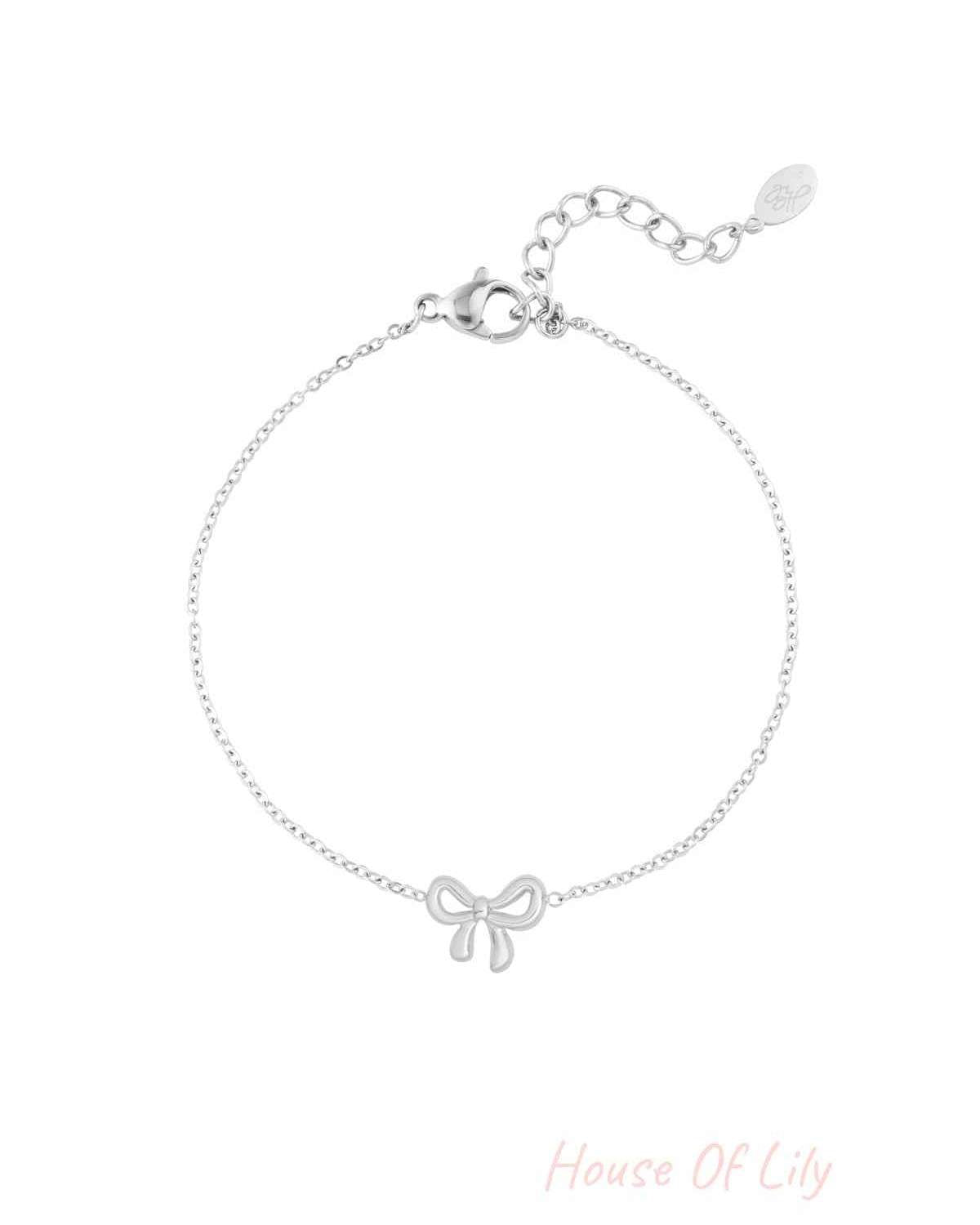 Silver bow charm bracelet with delicate chain and lobster clasp on white background
