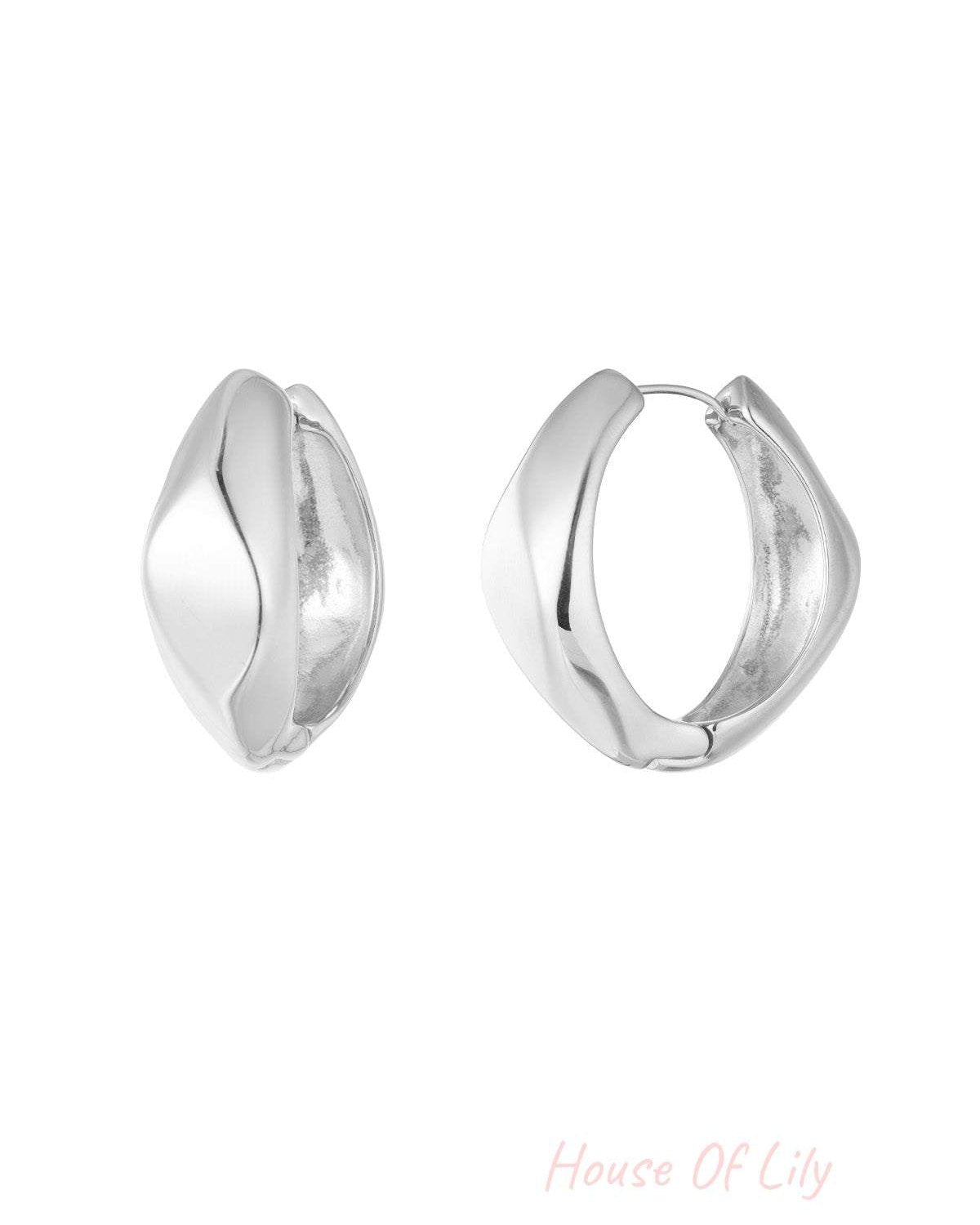 Front view of silver polished twist hoop earrings showing their sculptural twisted shape on white background.
