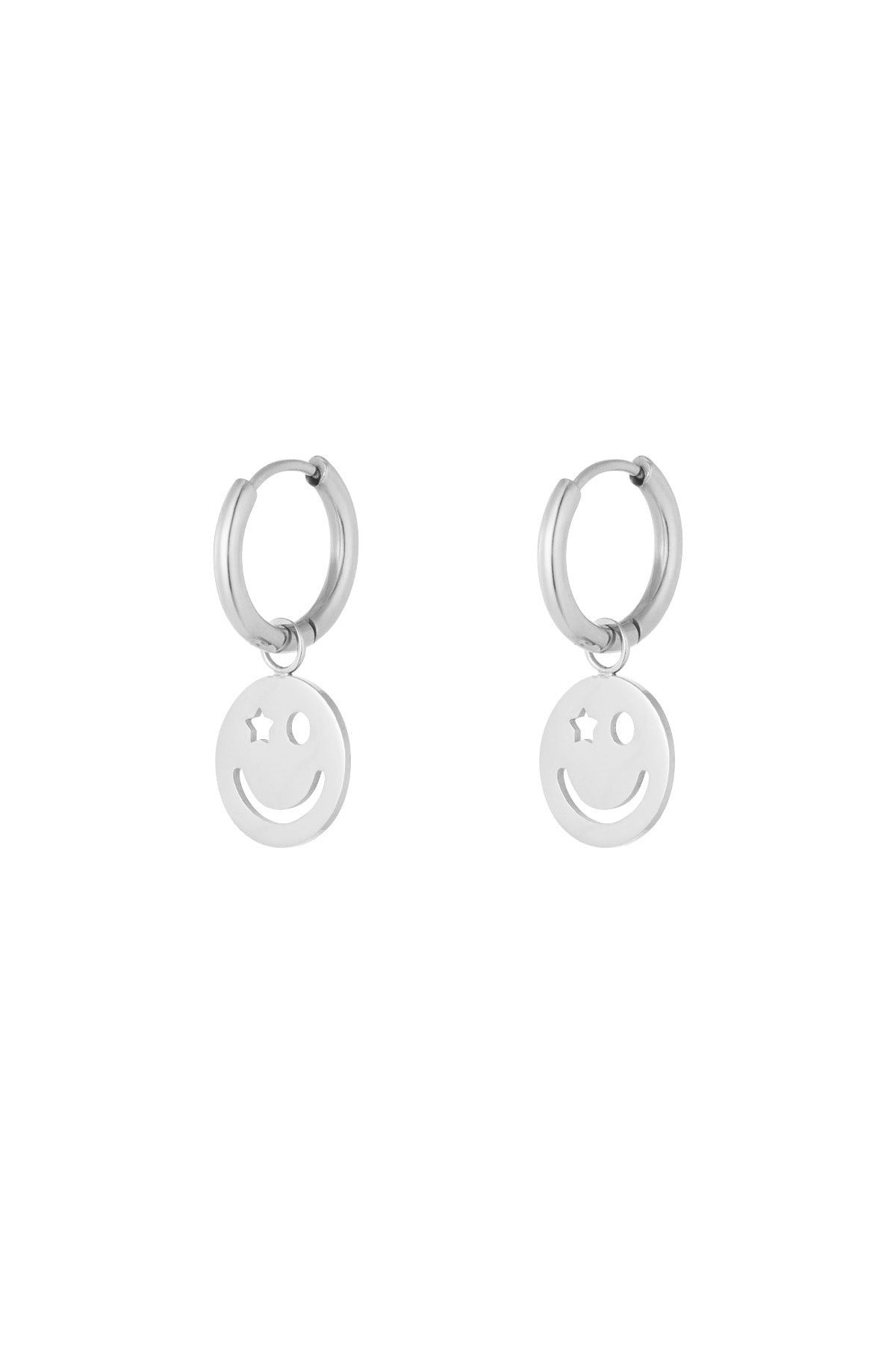 Pair of silver hoop earrings with dangling smiley face charm featuring one star eye and one circular eye on white background
