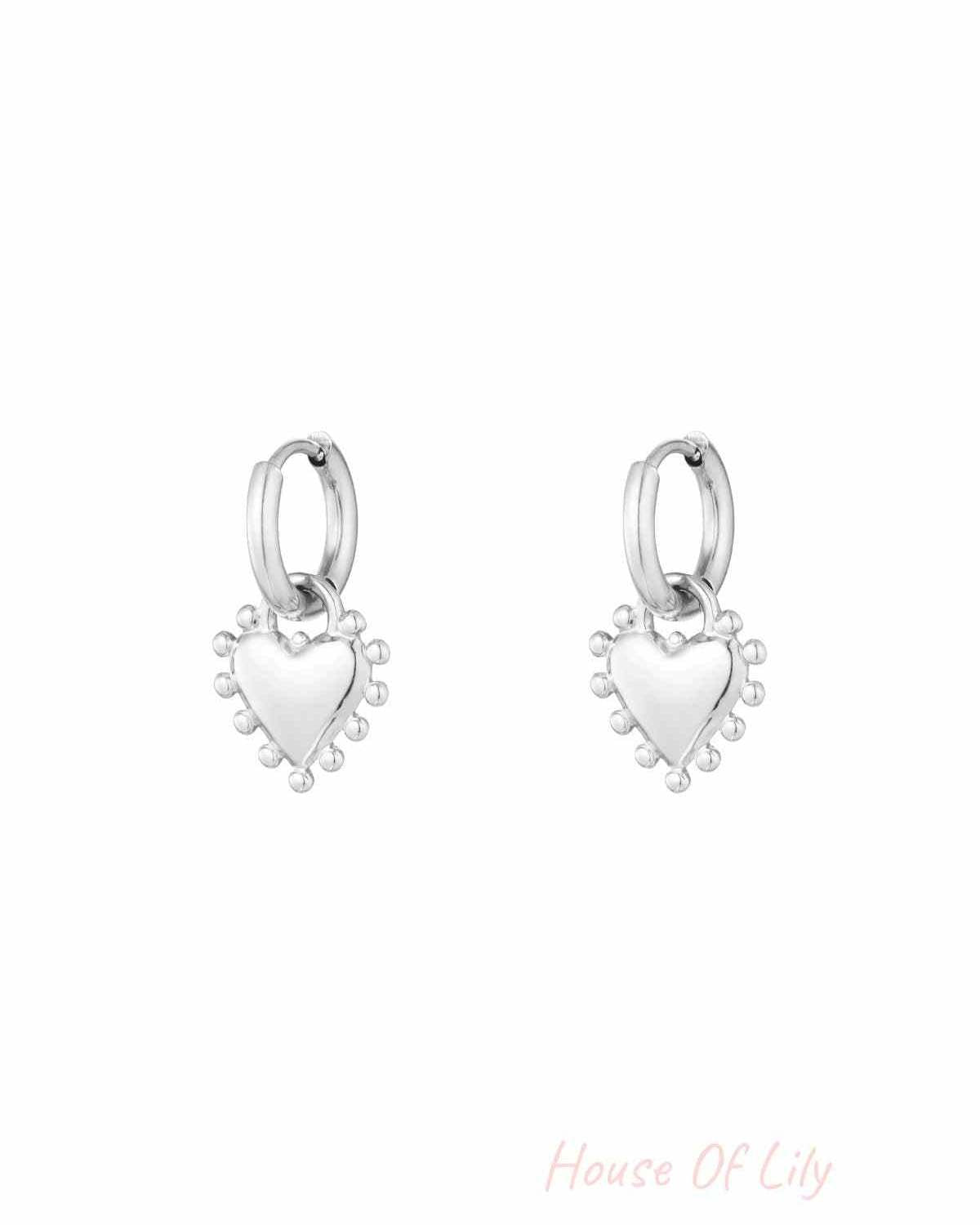 Pair of silver heart charm hoop earrings with beaded edge detail on white background