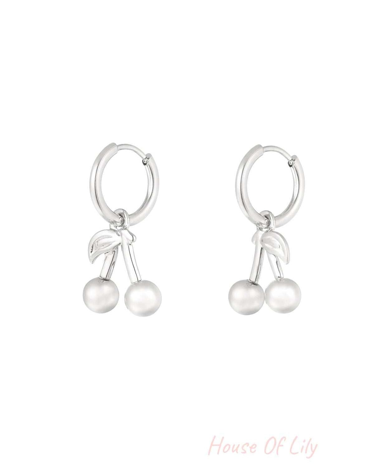 Silver-tone hoop earrings with cherry-shaped dangling charms made of stainless steel on a white background