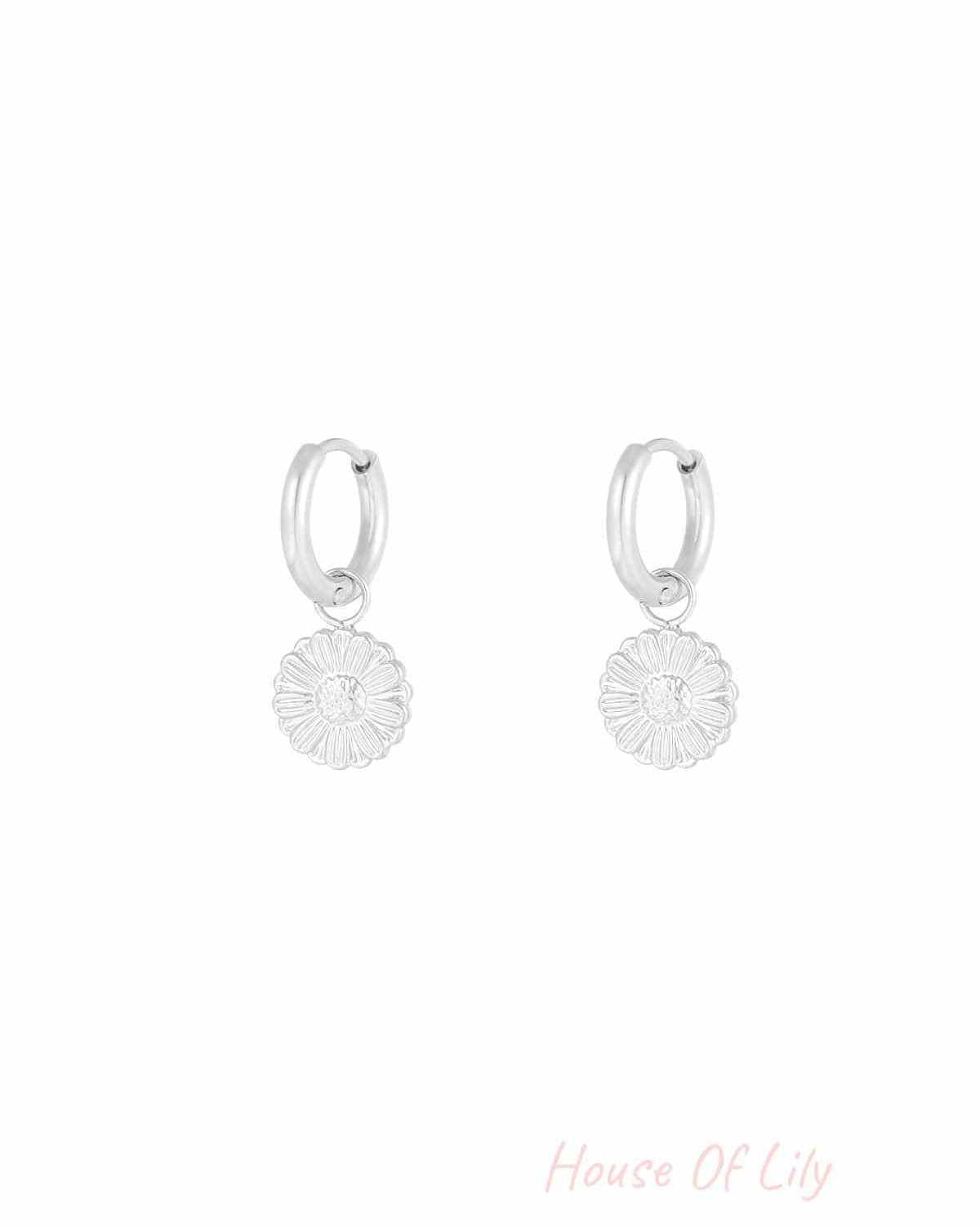 Silver hoop earrings with detailed daisy flower charms on a plain white background