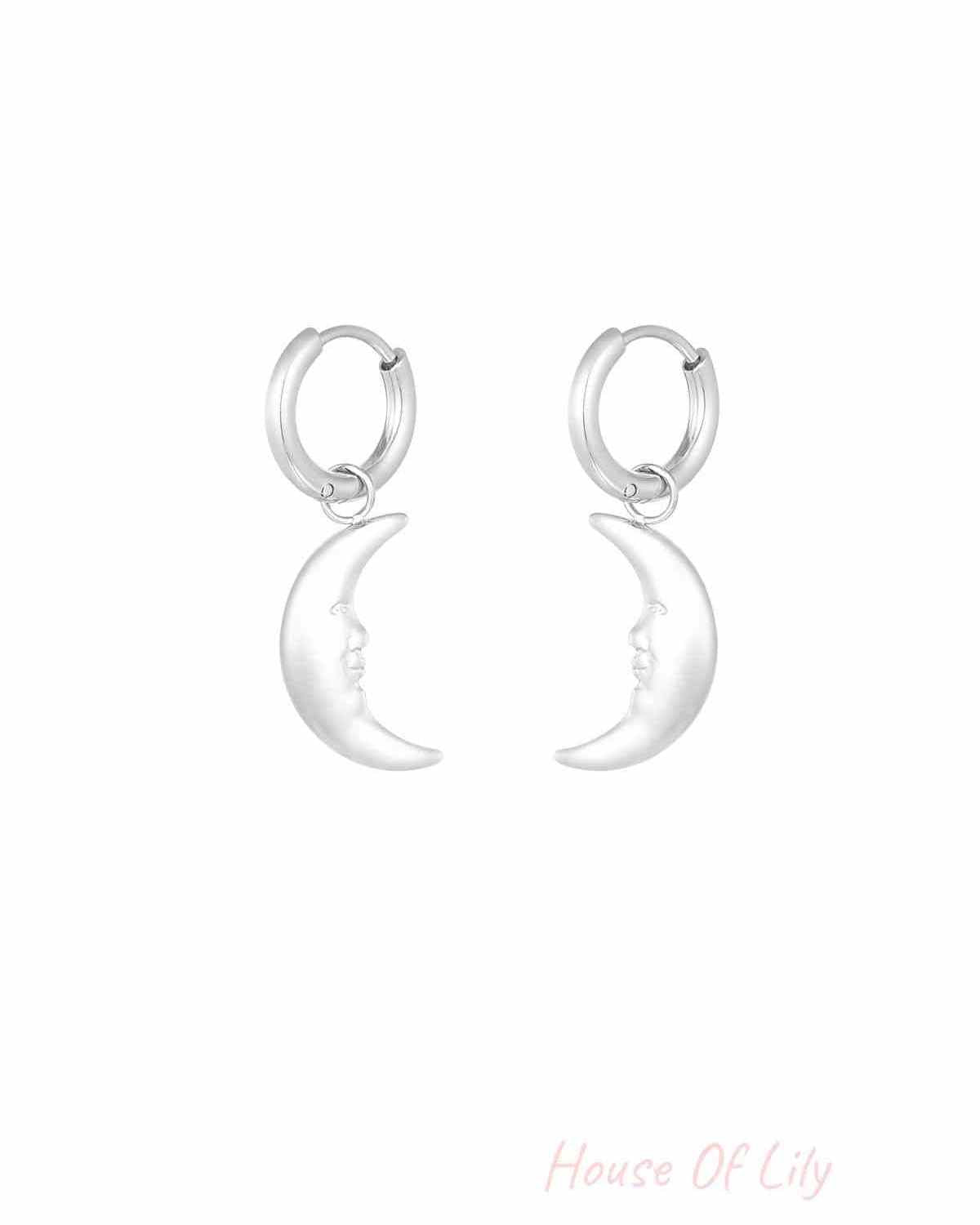 Pair of silver crescent moon face dangling hoop earrings on white background