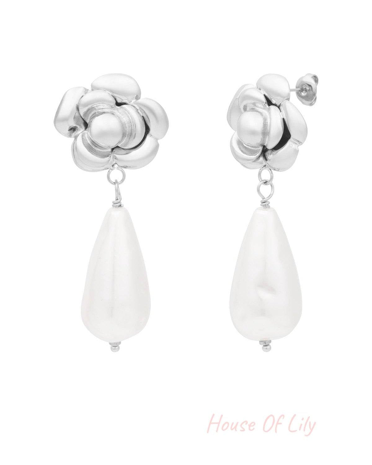 Silver rose shaped earrings with white teardrop pearl drops isolated on white background