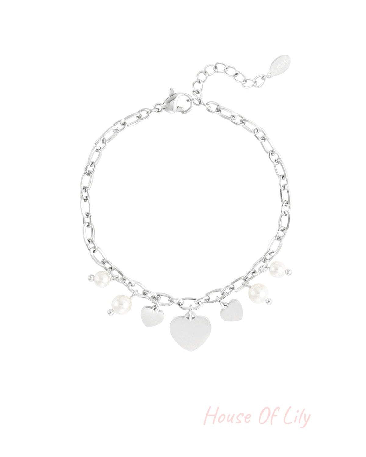 Silver-tone charm bracelet with heart and pearl charms on plain white background.