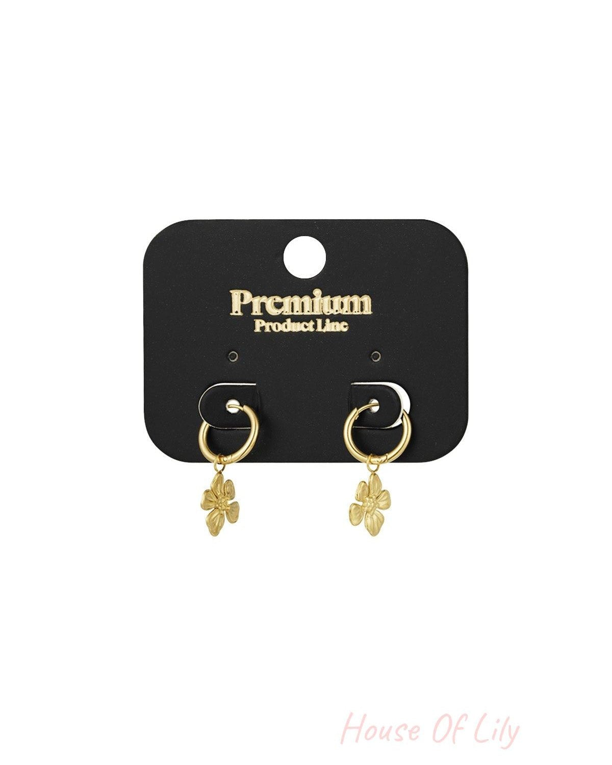 Gold floral charm hoop earrings displayed on a black premium product line card