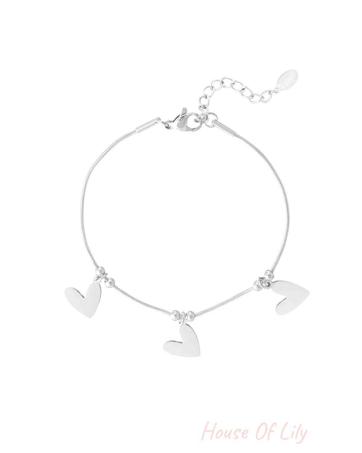 Silver heart charm bracelet with three flat heart pendants and adjustable chain on white background