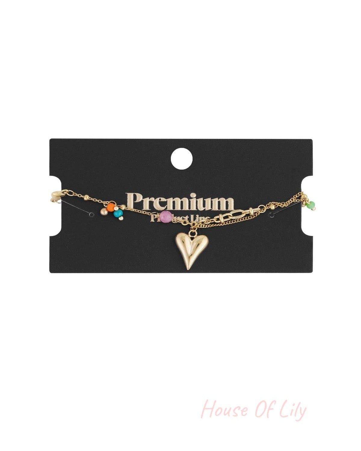 Golden charm bracelet displayed on a black 'Premium Product Line' card with vibrant colour beads and heart charm