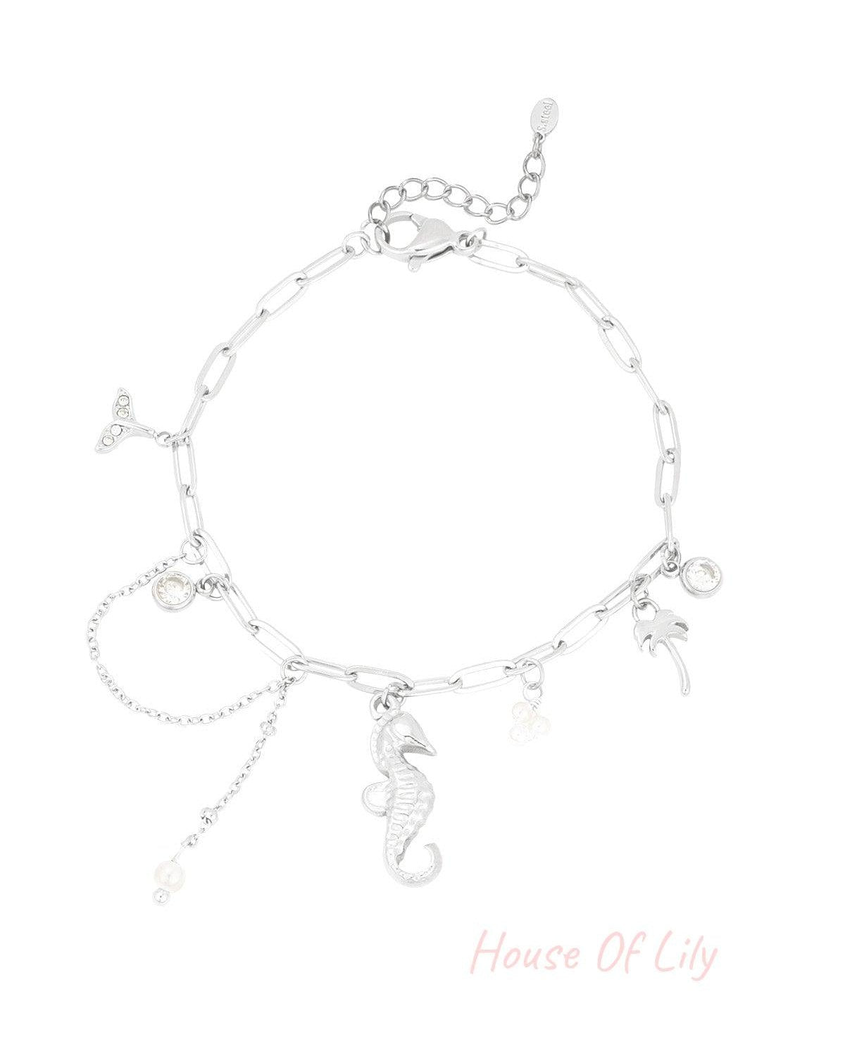 Silver charm bracelet displayed on black card labelled Premium Product Line with ocean-themed charms