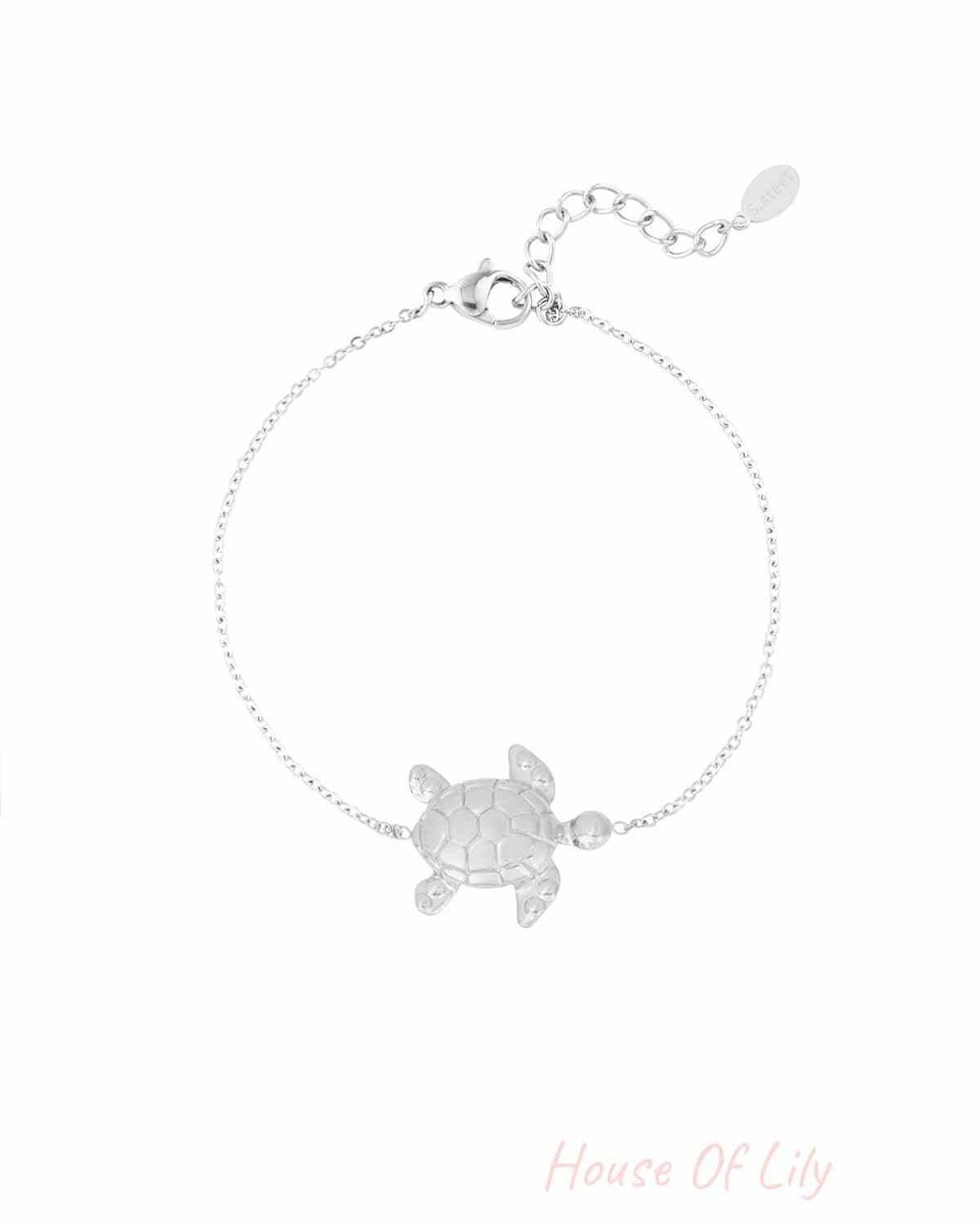Close-up of a delicate silver bracelet featuring a detailed turtle charm with an adjustable chain clasp