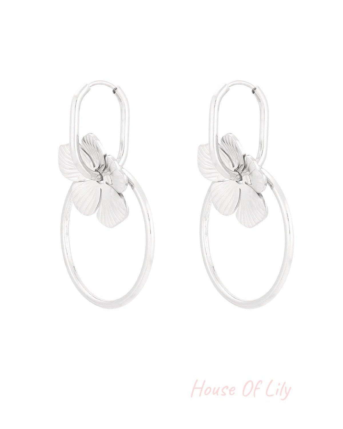 Pair of silver-tone floral hoop drop earrings with flower charms and circular hoops on white background