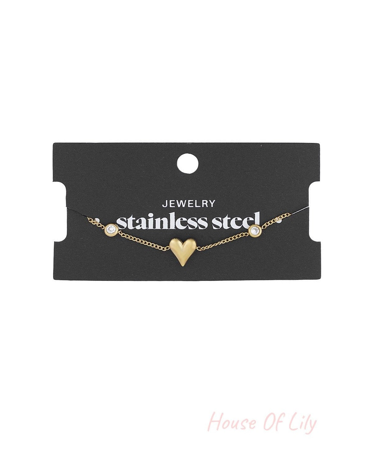 Gold tone heart charm bracelet displayed on black card labelled 'stainless steel jewelry'