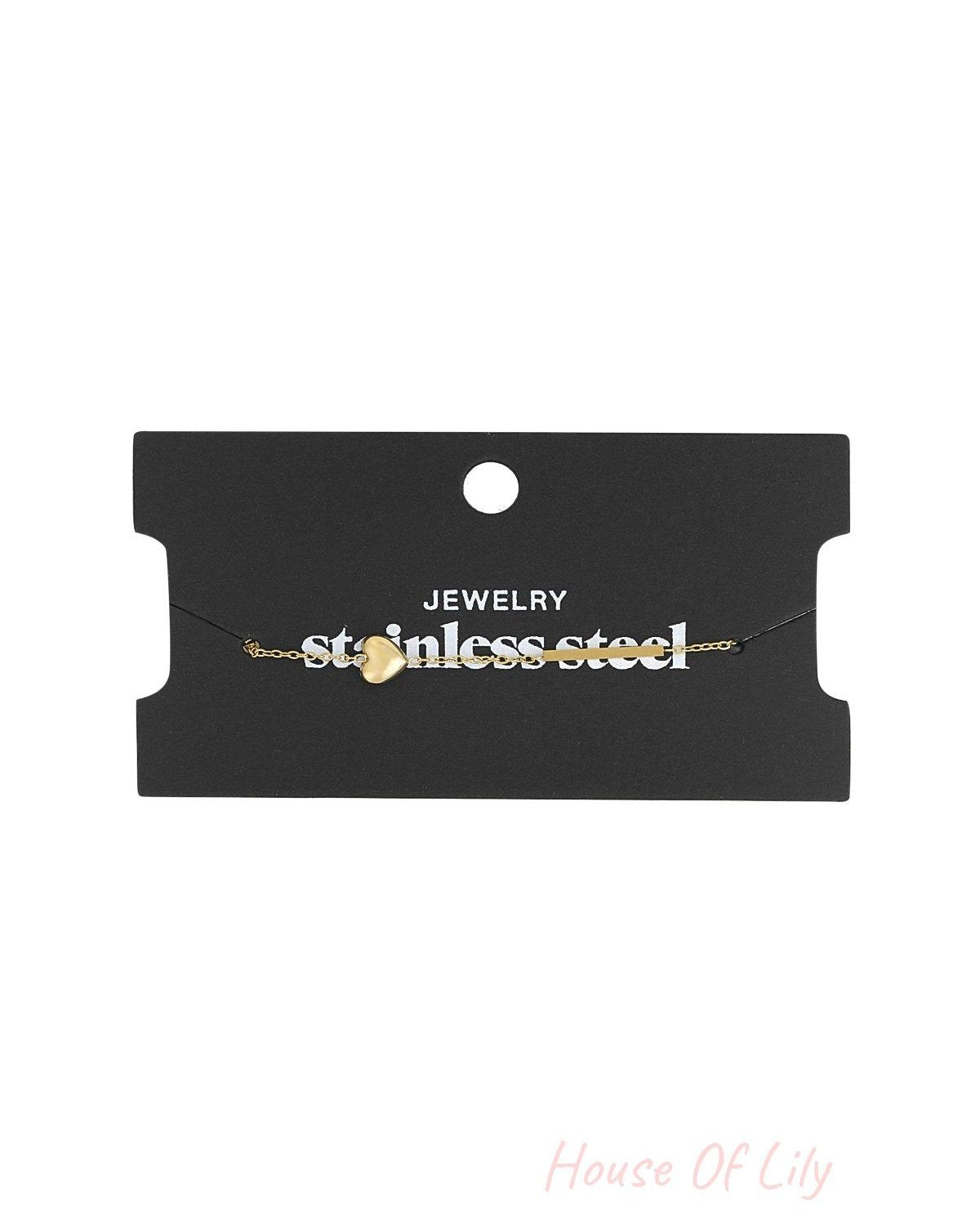 Gold heart charm bracelet displayed on black jewellery card labelled 'stainless steel'