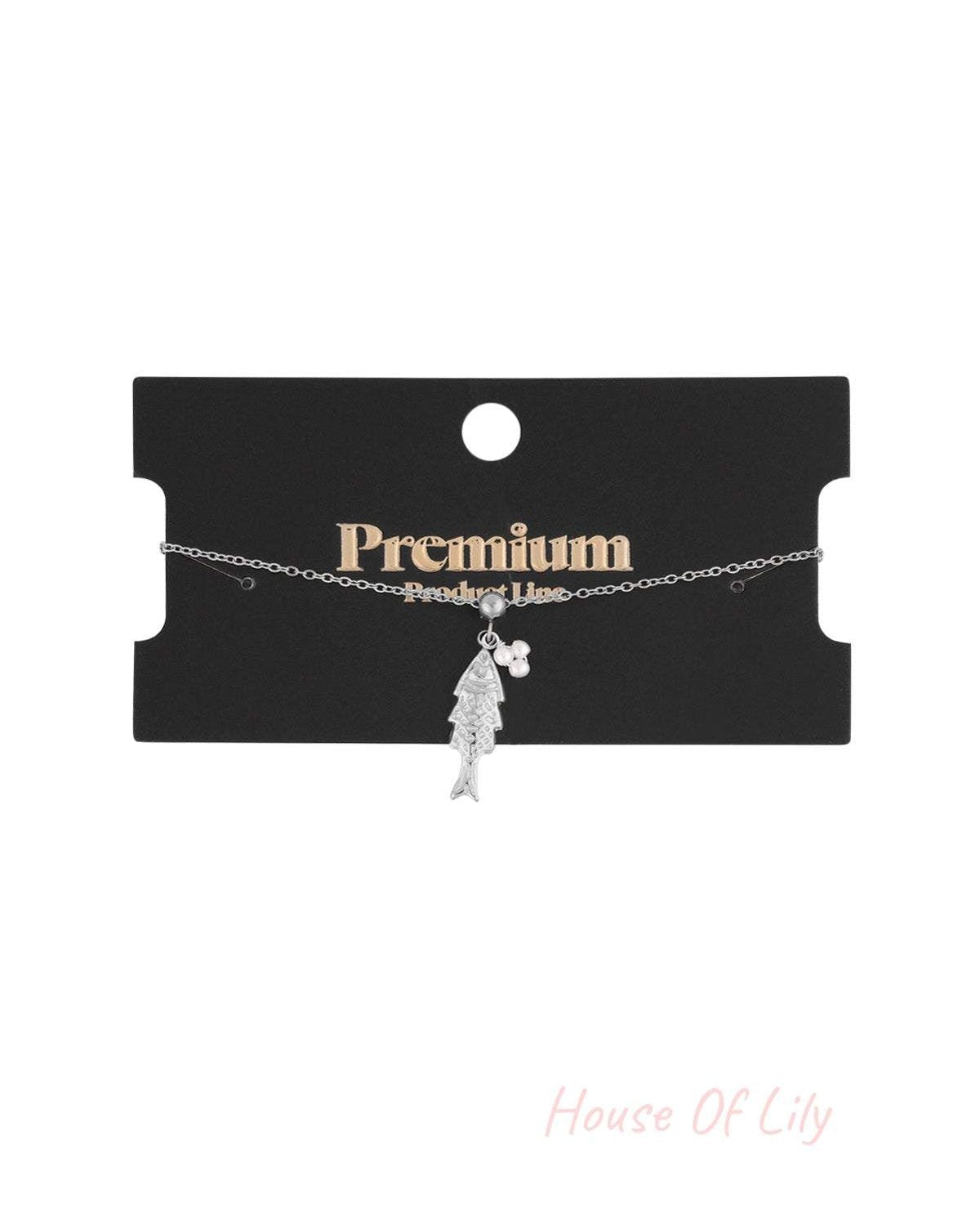 Silver tone fish pendant charm bracelet shown on a black premium product line display card