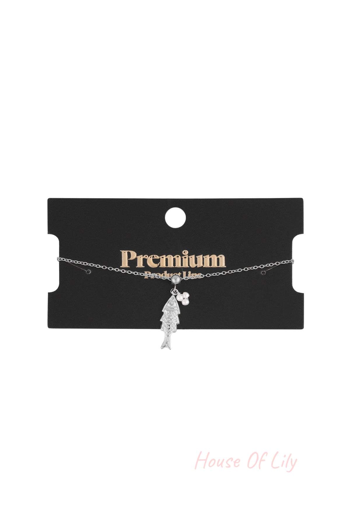 Silver tone fish pendant charm bracelet shown on a black premium product line display card