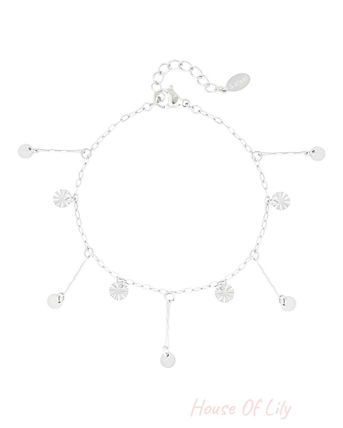 Silver coin charm bracelet laid flat, featuring dainty dangling coins and textured sunburst charms on chain