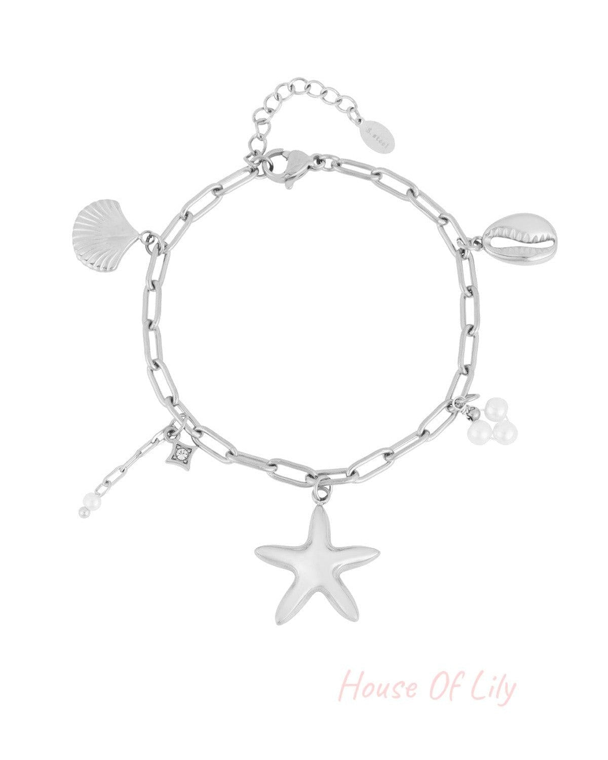 Silver-tone chain link charm bracelet with starfish, shell, cowrie shell and pearl charms laid flat on white background