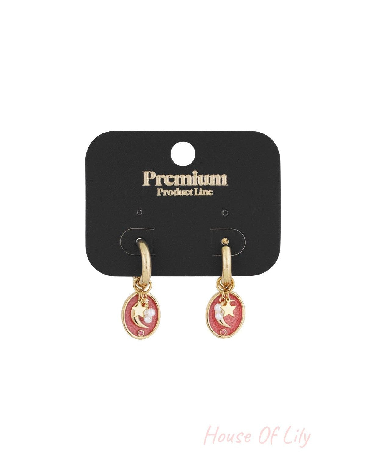 Gold-tone hoop earrings with pink enamel crescent moon and star charms displayed on black premium product card