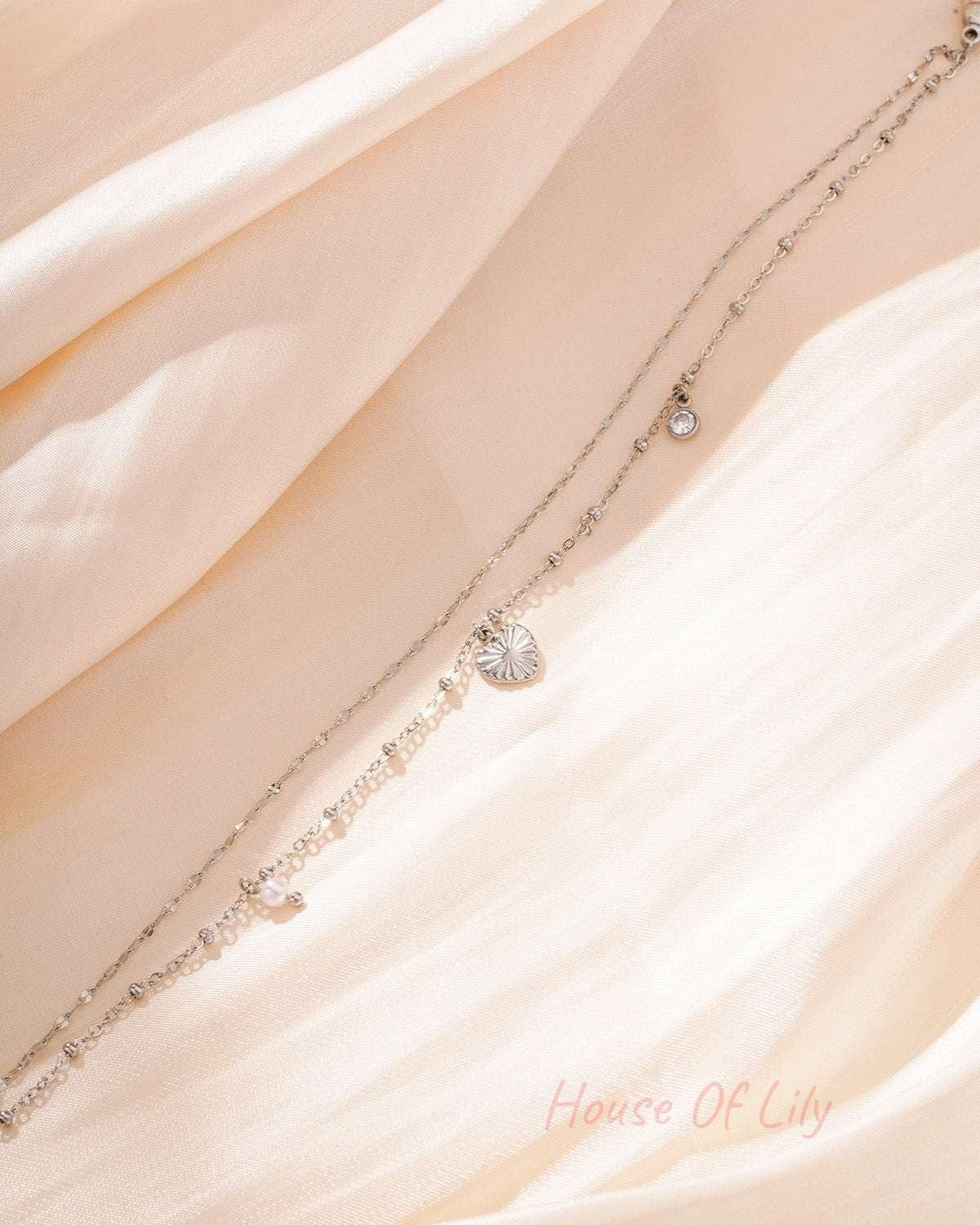 Gold charm bracelet with heart, pearl and crystal charms on a white background