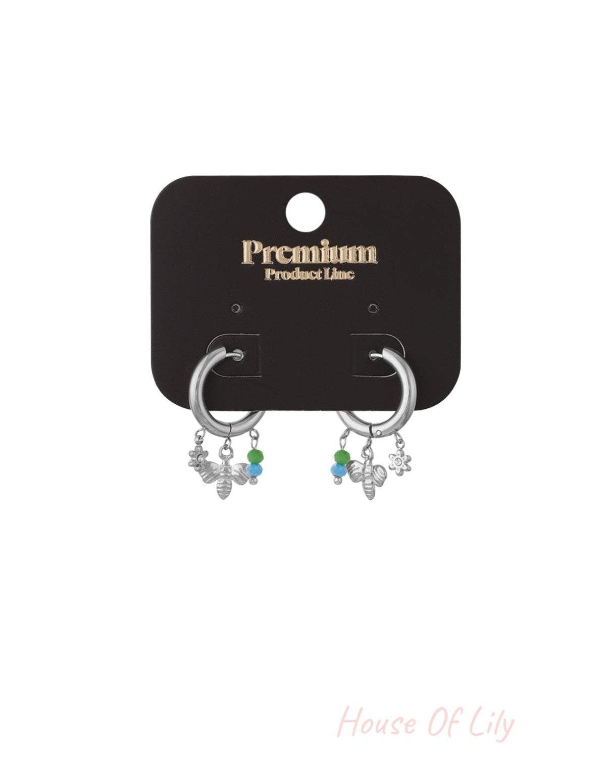 Silver charm hoop earrings with bee, flower charms and green-blue beads on black card