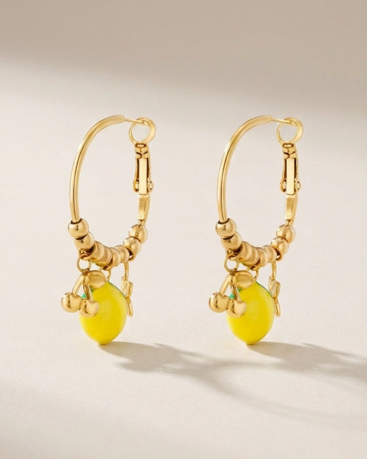 Gold hoop earrings featuring beaded detailing with yellow lemon and small gold cherry charms.