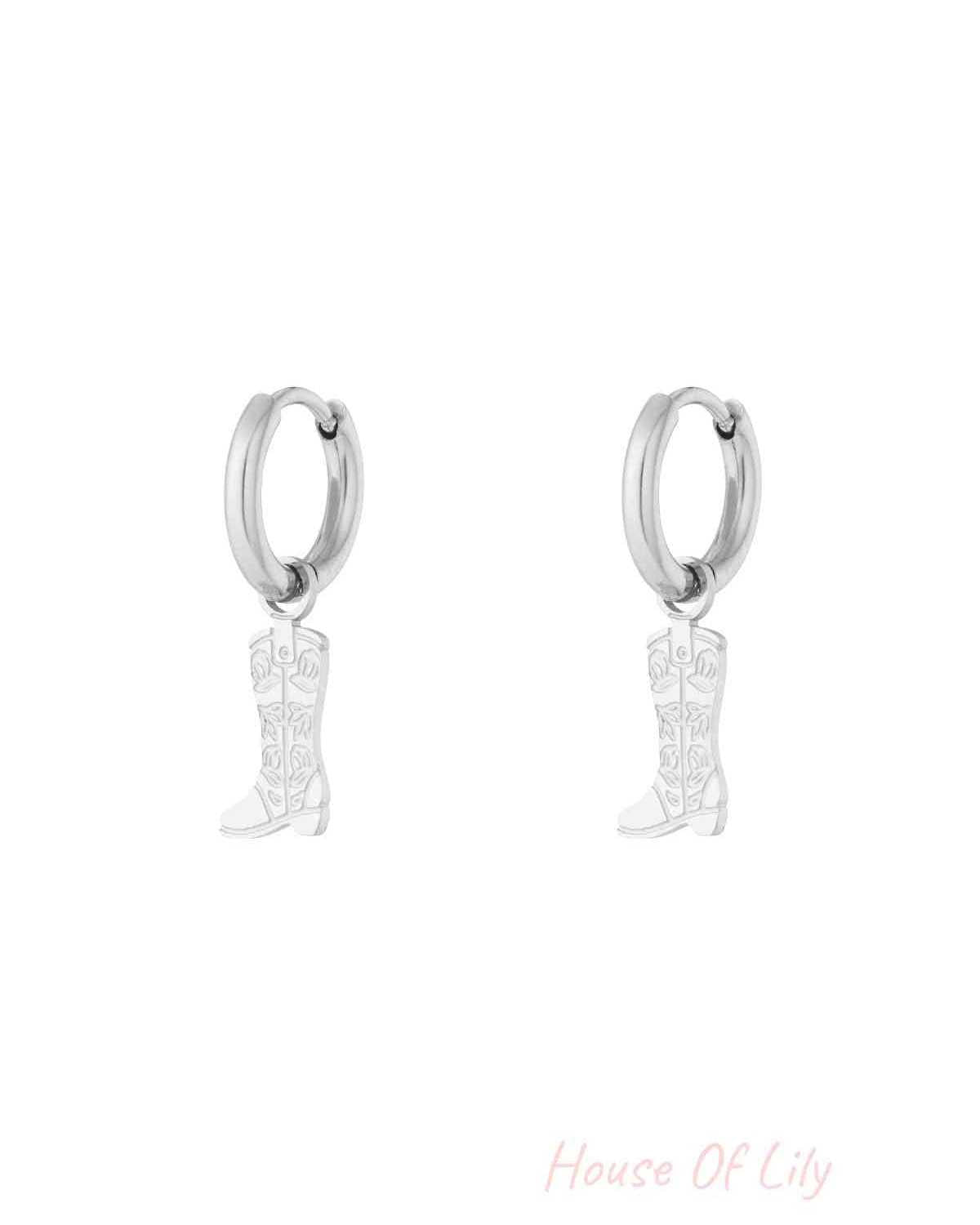 Pair of silver hoop earrings with hanging cowboy boot charms featuring floral detail on white background