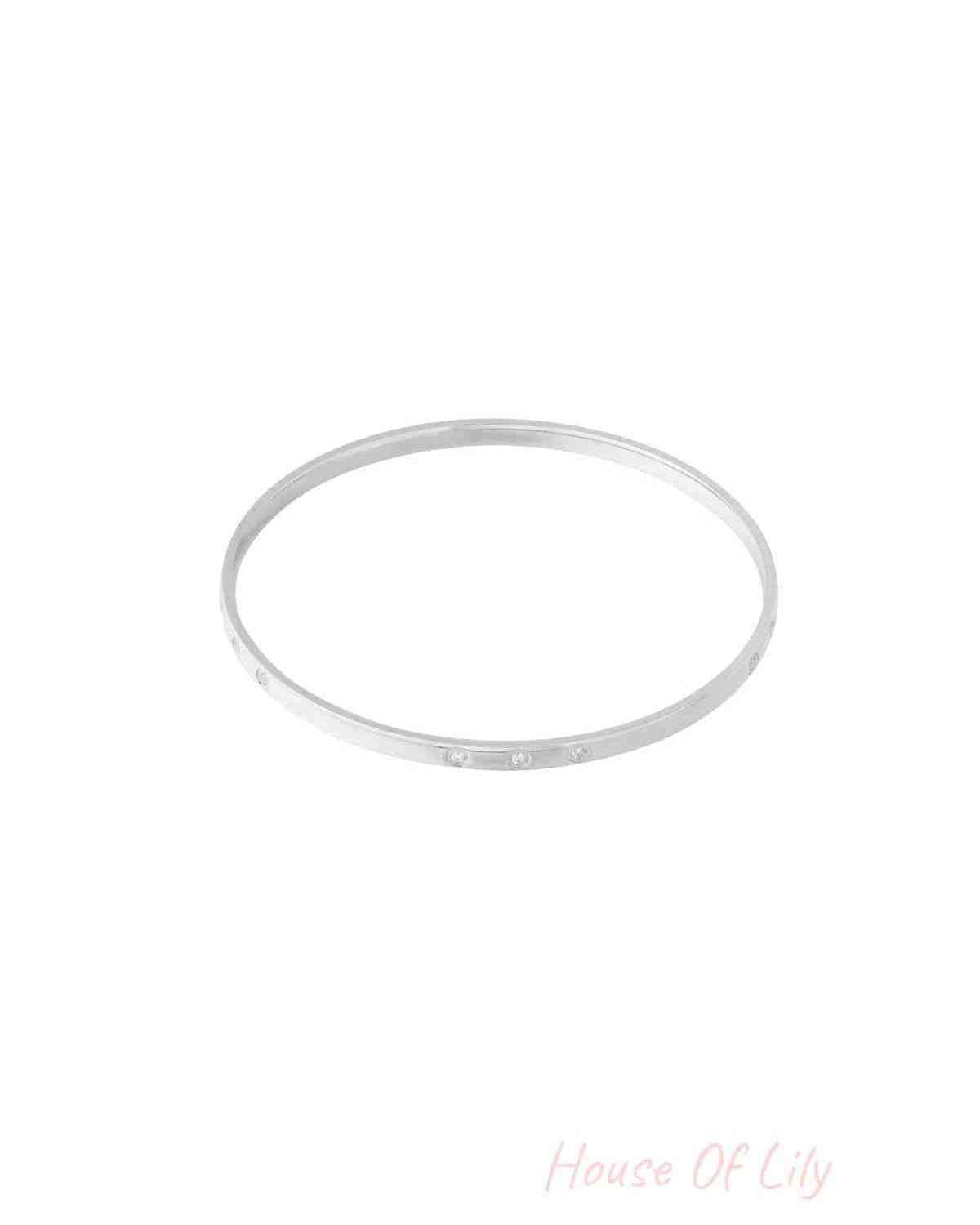 Slim silver bangle with small rhinestone accents photographed on a white background