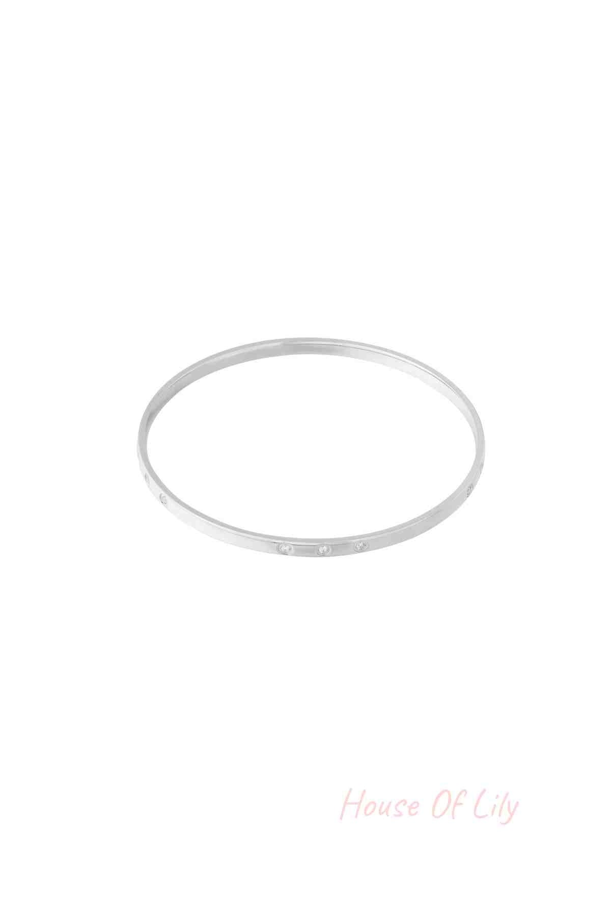 Slim silver bangle with small rhinestone accents photographed on a white background