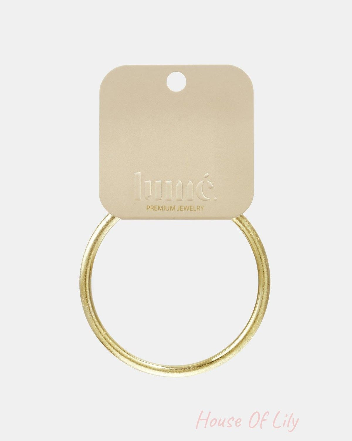 Simple gold-toned round bangle bracelet attached to a branded beige display card.