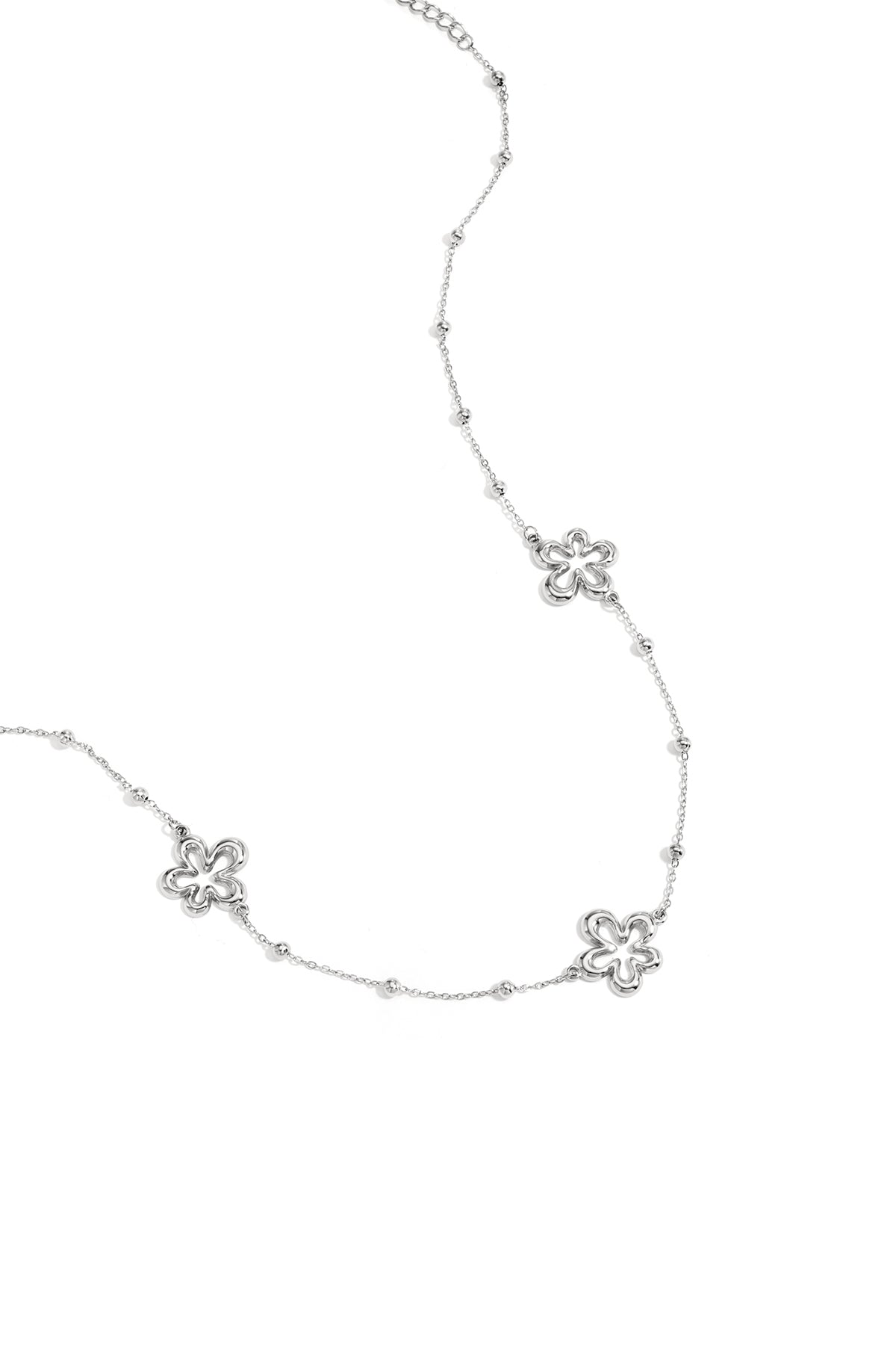 Close-up of silver necklace variant featuring the same hollow flower charms and bead accents on white background