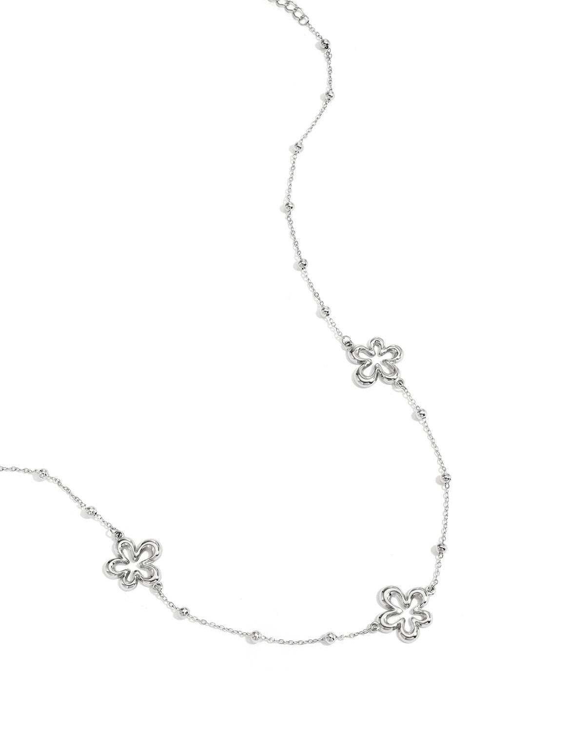 Close-up of silver necklace variant featuring the same hollow flower charms and bead accents on white background